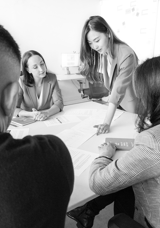A diverse group of people engaged in discussion around a table covered with papers and documents.