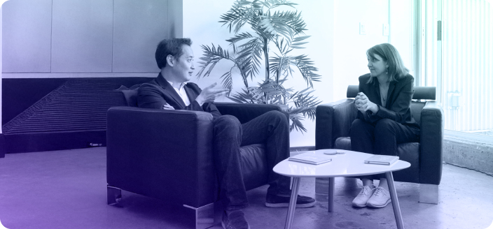 Two people engaged in conversation while sitting in a chair, sharing ideas and expressions.